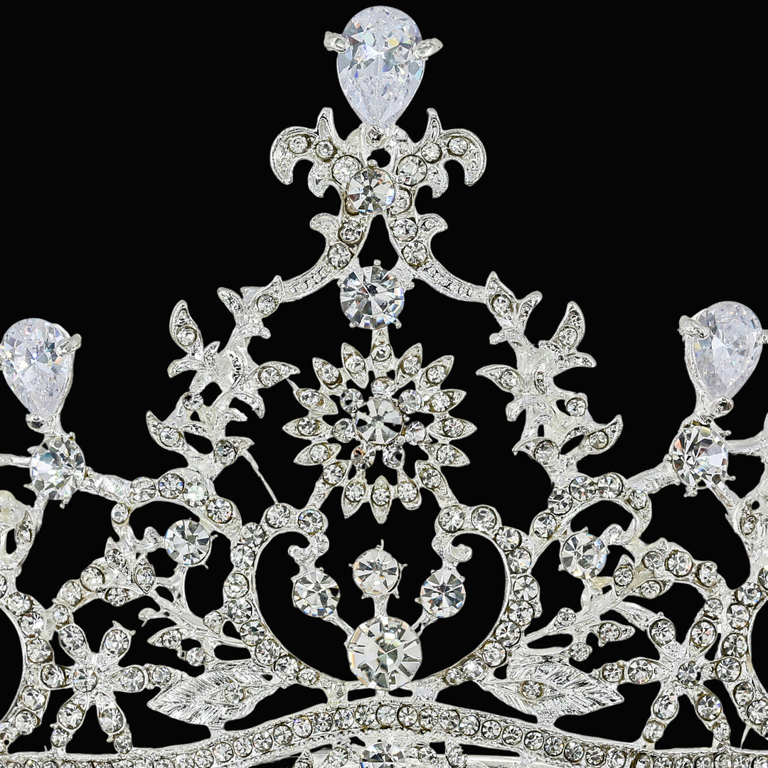 Macro close-up of a silver-tone crown featuring prong-set pear-cut and round-cut clear rhinestones in filigree metalwork.