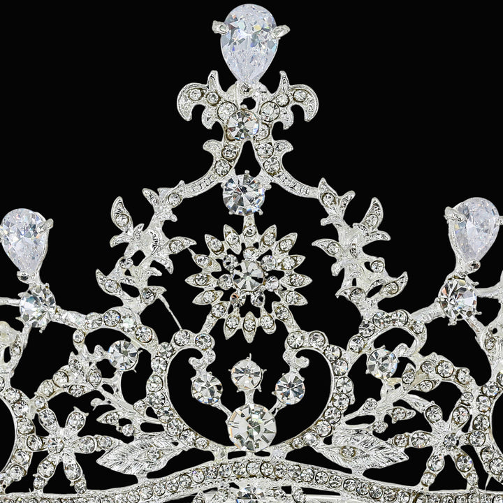 Macro close-up of a silver-tone crown featuring prong-set pear-cut and round-cut clear rhinestones in filigree metalwork.
