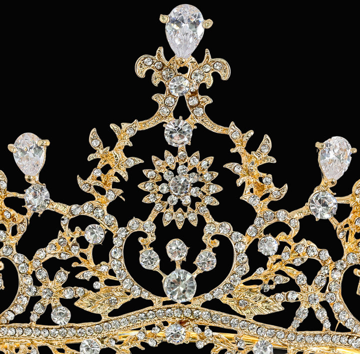 Macro close-up of a gold-plated tiara featuring teardrop-cut crystals, pavé-set round rhinestones, and filigree wirework.