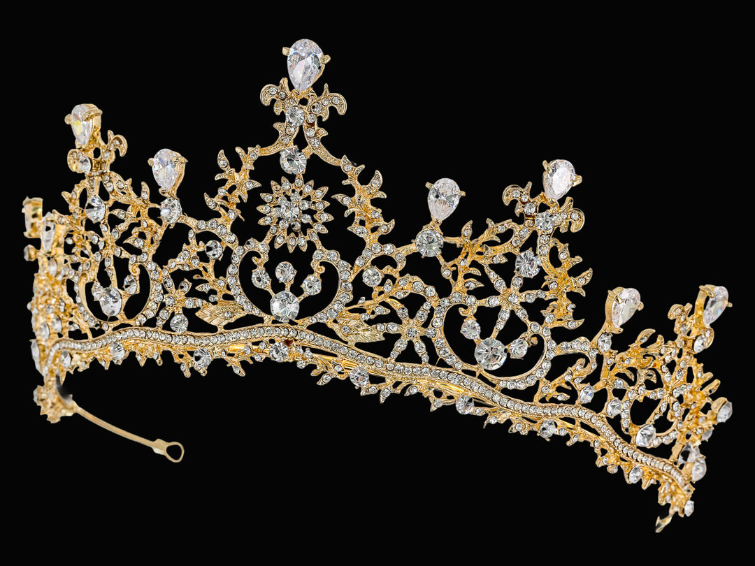 Side-angle shot of a gold-plated tiara with pear-shaped cubic zirconia, round clear stones, and intricate filigree scrollwork.